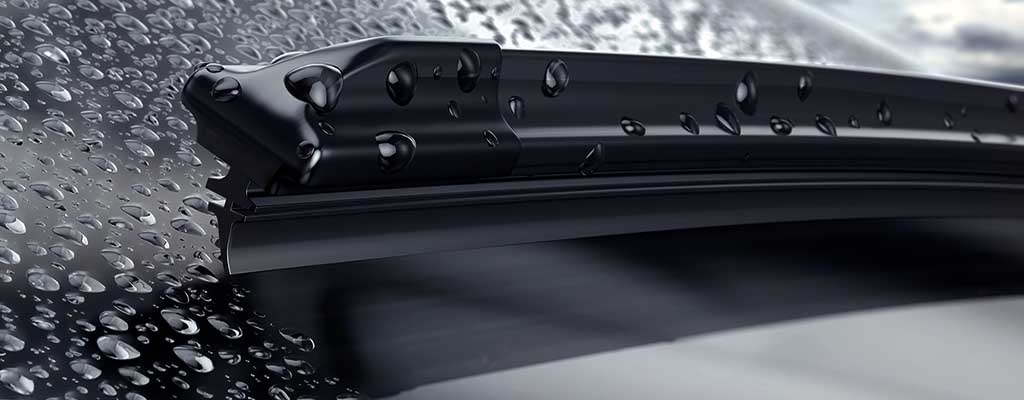 Fotografija prikazuje brisalec za avto, čigar metlica brisalcev skrbi za dobro vidljivost skozi vetrobransko steklo v dežju.