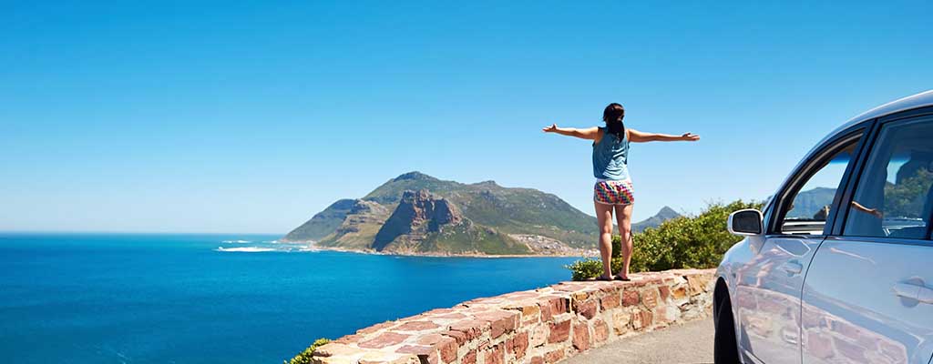Fotografija prikazuje voznico, ki brezskrbno uživa na dopustu, saj je avto pripravila na daljšo pot.