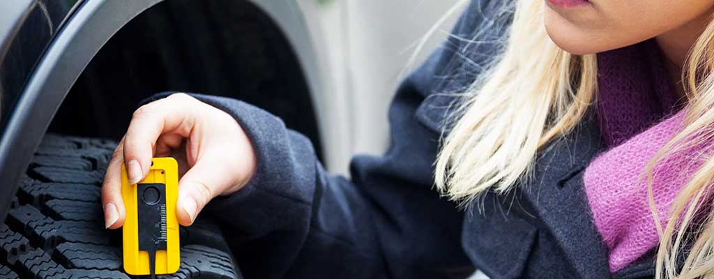 Fotografija prikazuje, kako lahko z napravo preverimo, ali je avto guma obrabljena ter koliko meri profil pnevmatike.