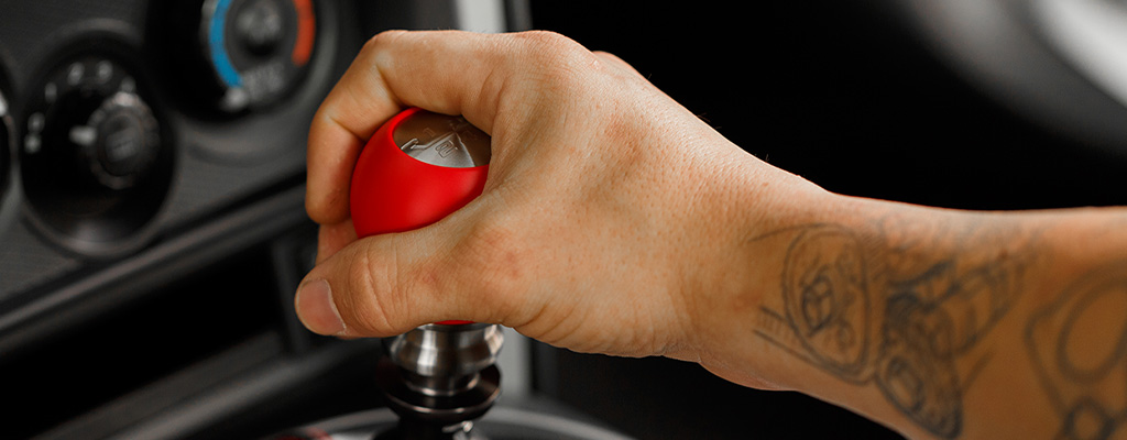 Na fotografiji je roka voznika, ki med vožnjo počiva na menjalniku.