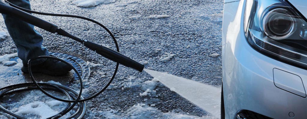 Fotografija prikazuje ročno čiščenje avtomobila pozimi.